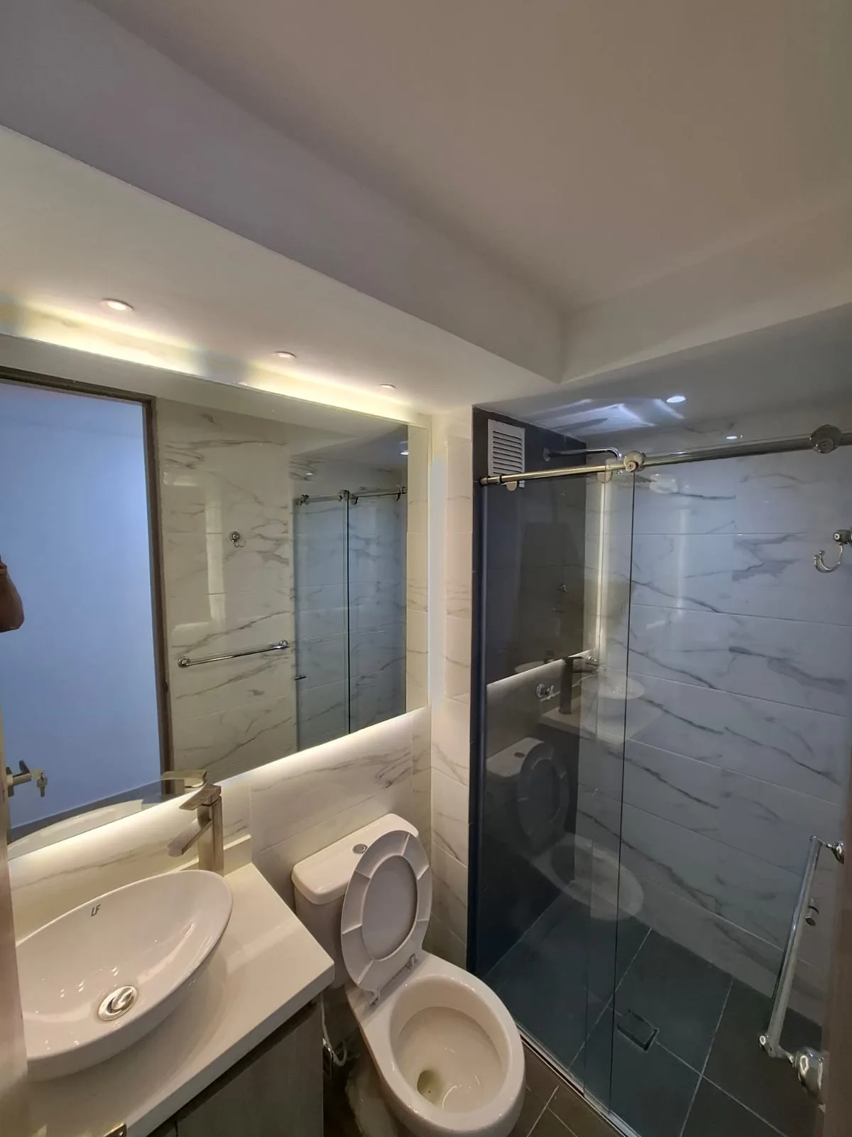 Baño con enchape en mármol y ducha en vidrio templado