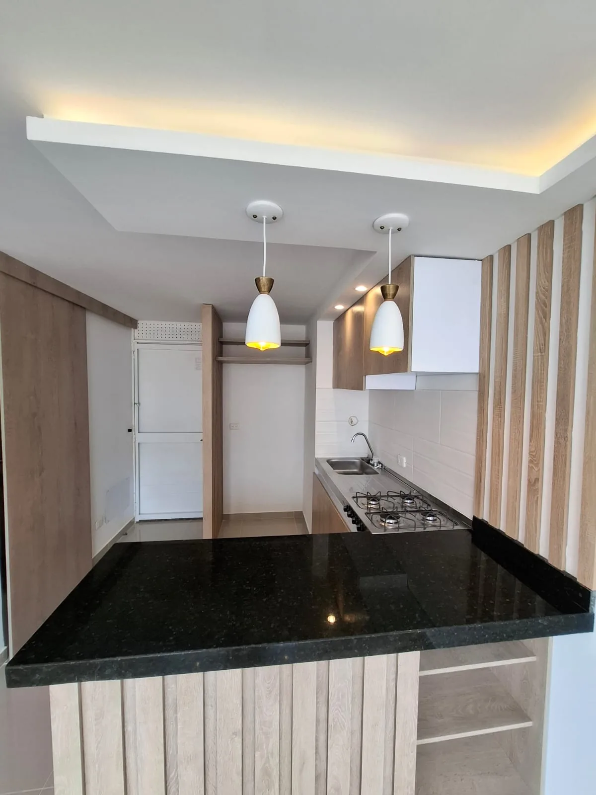 Cocina con mesón en granito negro e iluminación colgante