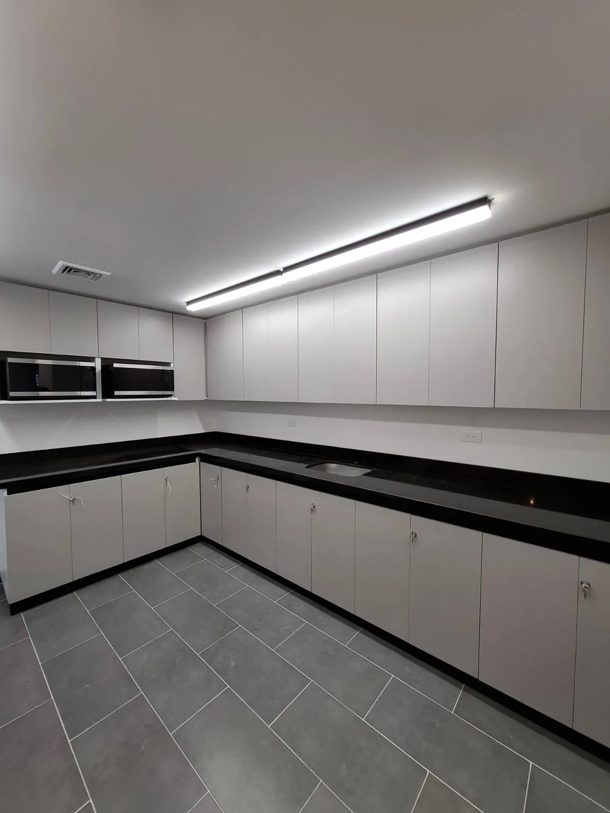 Cocina en L con muebles blancos y mesón negro