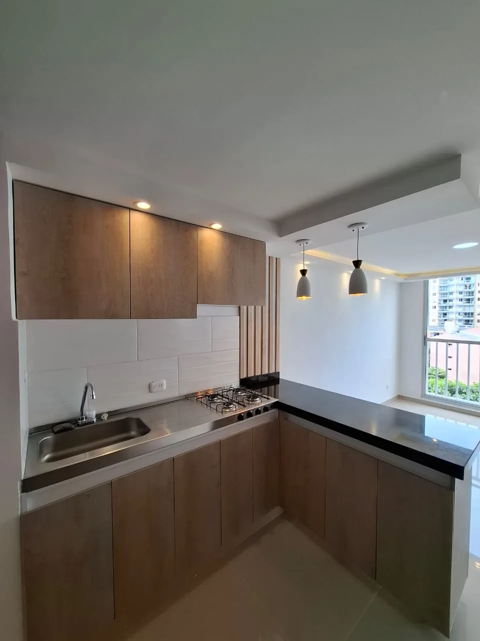 Cocina en U con muebles en madera y mesón en granito negro